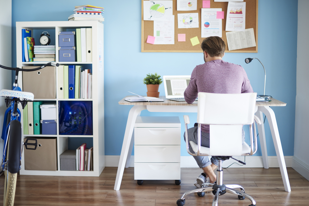 A man sitting in a chair at a desk working from home.